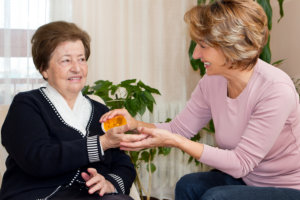 caregiver giving medicine on elderly woman