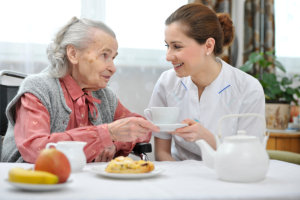 caregiver serving a cup to elderly woman