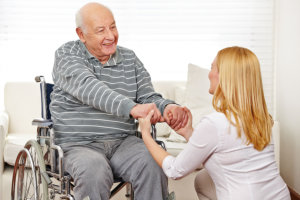 caregiver holding hands of the elderly man in wheelchair